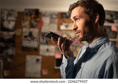 Detective working in his office using voice recorder on cell phone. Copy space