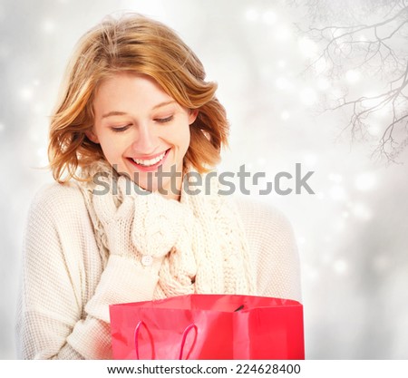 Beautiful young woman looking at a red gift bag 
