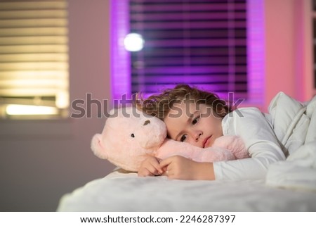 Child cannot sleep on bed at night in bedroom. Kid having sleeplessness. Kid boy sleeping in bed with night light. Royalty-Free Stock Photo #2246287397