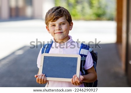 Happy little kid boy with backpack or satchel. Schoolkid on the way to school. Healthy adorable child outdoors On desk Last day second grade in German. School's out Royalty-Free Stock Photo #2246290927