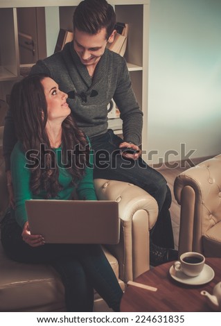 Young couple with laptop and coffee behind table