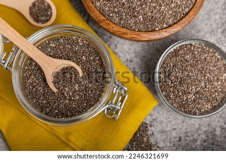 Chia seeds in a spoon and bowl on a black texture background.Superfood and axiontidant. Diet. Close-up. Place for text. Copy space.