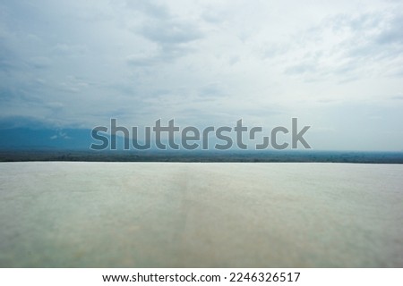 Closeup white empty floor with panorama view of horizontal line of mountain view with cloudy sky 
