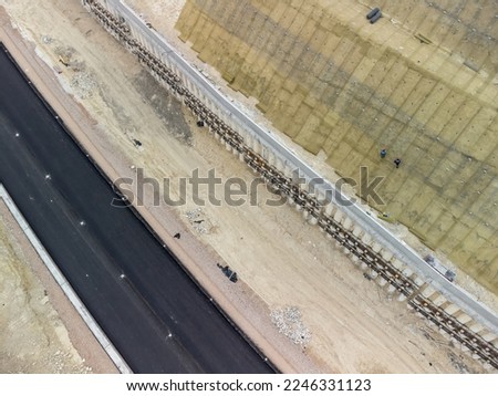 Mountain road constraction. Workers reinforce the slope over the new road. Road construction in progress on slope nature canyon. Infrastructure development and logistics. Aerial drone shot