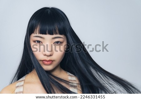 Young Asian girl blowing her hair. Hair care concept. Cosmetics. Royalty-Free Stock Photo #2246331455
