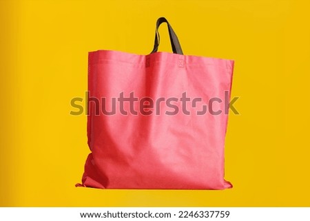 Non Woven Fabric Shopping Bag isolated on yellow background. Tote Bag. Environment friendly Climate change disposable bag with a yellow color background. Grocery recycle item
