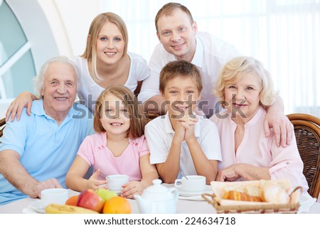 Portrait of happy senior and young couples and their children sitting by dinner table