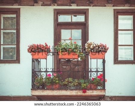 Picture with a beautiful rustic house. Front view  of a balcony with flower pots in Veliko Tarnovo, Bugaria.