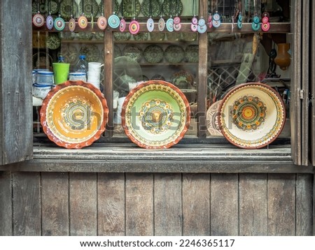 Ornamented bulgarian traditional clay plate home made. Craftsman window store on Samovodska Charshiya street  in Veliko Tarnovo, Bulgaria. Royalty-Free Stock Photo #2246365117