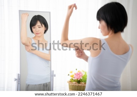 Diet image of a young woman checking her upper arm in the mirror Royalty-Free Stock Photo #2246371467