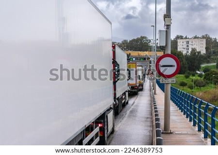 Customs or next border sign next to a line of trucks waiting to cross.