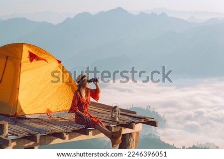 Asian traveller woman take a photo by her camera on the top of mon Kalakojo at Tak with sunrise and fog background on the morning time, Winter season of view point near Chiang mai, Thailand