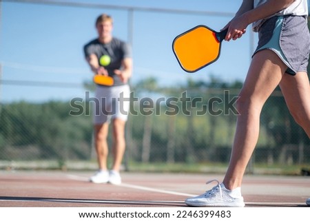 couple playing pickleball game, hitting pickleball yellow ball with paddle, outdoor sport leisure activity. Royalty-Free Stock Photo #2246399483