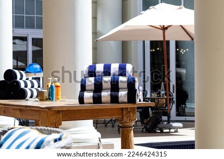 Folded navy and white pool towels on a table next to a pool.