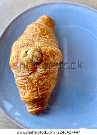 Closeup shot of a freshly baked croissant in a blue glass plate