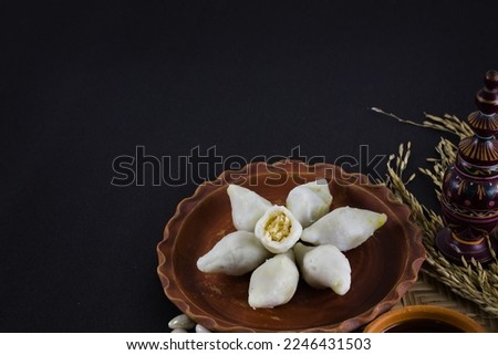 puli pithe or bengali rice flour dumplings with coconut fillings served on a clay plate with jaggery. shot against black background.this traditional dish made during poush sankranti or makar sankranti Royalty-Free Stock Photo #2246431503