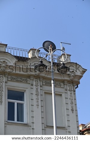 corner of historic building with decorated raised parapet and metal guardrail on pitched roof