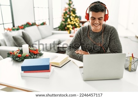 Young hispanic man studying sitting by christmas tree at home