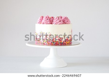 Cake on birthday with pink cream on a white background decorated with colorful sprinkles.