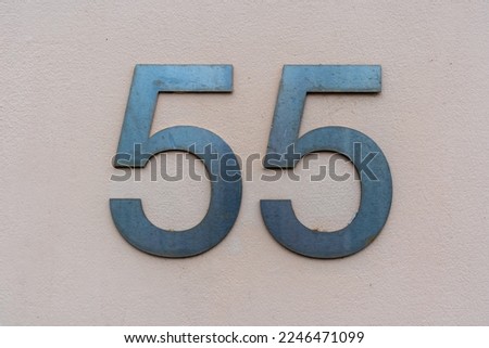 House number fifty five in steel lettering on a pink rendered wall