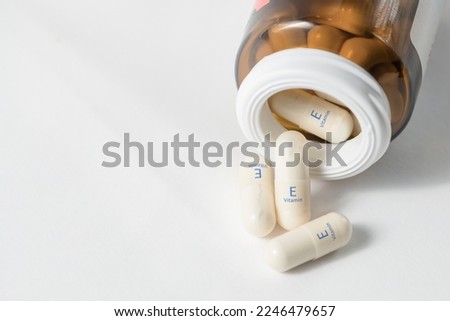 Vitamin E. Capsules with tocotrienol, an antioxidant that regulates energy metabolism in muscles. White capsules of vitamin E or tocopherol are scattered on the table with copy space. Royalty-Free Stock Photo #2246479657