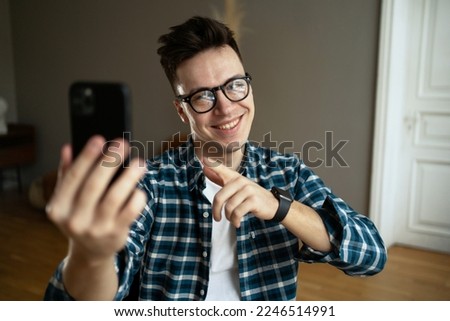 A man in a shirt and glasses, online communicates with friends by phone video communication, smiles and positively answers questions.