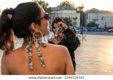 Women tourists in an European city taking pictures of each other with a vintage camera
