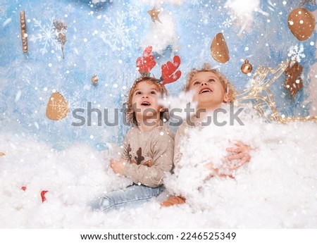 Little boys in sweaters in the winter forest. Winter wonderland setup with snow, stars and Christmas deer props. Family photo.
