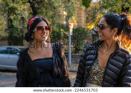 Two female tourists enjoy walking through the streets of an European city at sunset with backlight