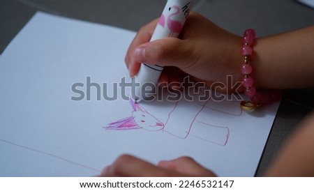 a little girl drawing a colorful cat with a pen.