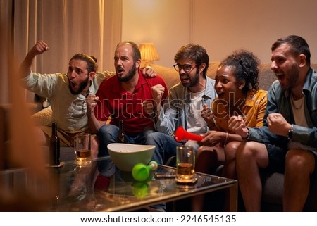 Caucasian joyful happy young friends woman and man at home hanging together cheering for favorite team and it winning match. People watching game on TV on sport channel, fun concept Royalty-Free Stock Photo #2246545135
