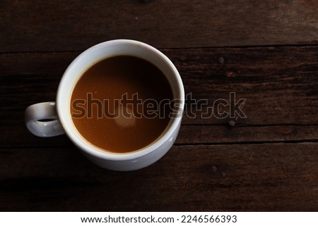 a cup of coffee in a white cup on a wooden table