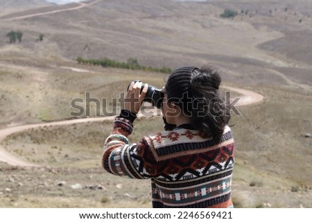 Male tourist in landscape of the Andes of South America with a camera in his hand. Concept of people, travel, tourism.