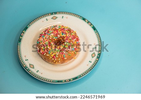 Donuts with various toppings made by home industry with palm sugar base in flat lay photo served on plate and turquoise background