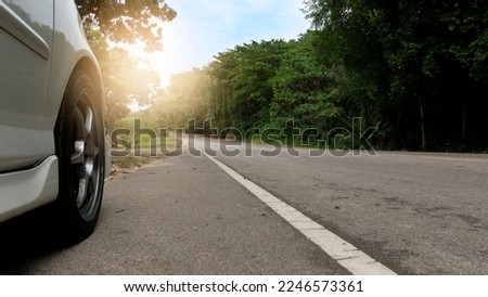 Car driving on the asphalt road. Beside front view of white car parking beside asphalt road. Green forest beside of the road under the sky. Royalty-Free Stock Photo #2246573361