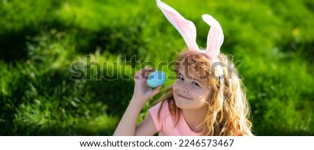 Easter bunny boy. Child in bunny ears hunting easter eggs outdoor on backyard. Easter egg hunt. Wide photo banner for website header design.