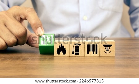 Hand choose cube wooden toy block stack with door exit sing or fire escape with fire prevent icon and fire extinguisher and emergency prevention or protection symbol for safety and rescue.