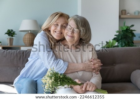 Happy peaceful caring senior daughter woman embracing, tightening elderly mom with affection, devotion, love, visiting old mother, congratulating on birthday, 8 march day, enjoying family leisure Royalty-Free Stock Photo #2246612355