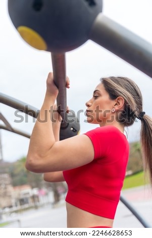 Fit woman in red outfit doing arm exercises on some bars, fitness and healthy active concept