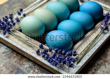 Happy Easter rustic background. DIY dyed various shades of blue Easter eggs and vintage wooden picture frame with dried lavender.