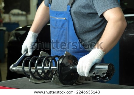 Repair and maintenance of the car at the dealership. An auto mechanic replaces the spring and shock absorber strut of the front suspension of the car. Royalty-Free Stock Photo #2246635143