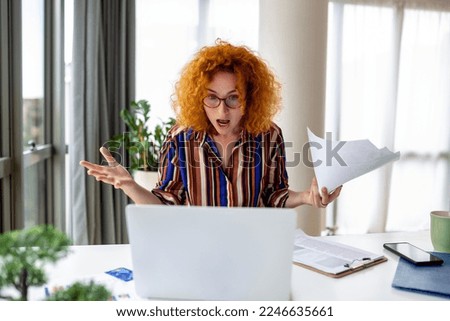 Shocked business woman using laptop at home, looking at screen, chatting, reading or writing email, sitting on couch, female student doing homework, working on research project online Royalty-Free Stock Photo #2246635661