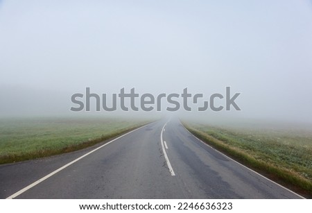 Empty asphalt road (highway) through the fields and forest. Thick fog. Concept autumn landscape. Transportation, dangerous driving, speed, freedom, travel, tourism, the way forward themes