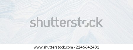Wide panoramic winter background with snowy ground. Natural snow texture. Wind sculpted patterns on snow surface. 