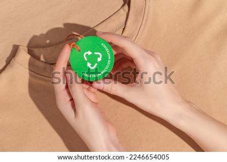 Hands hold Green paper label with inscription "Made from recycled materials". Ecology concept. Mockup.