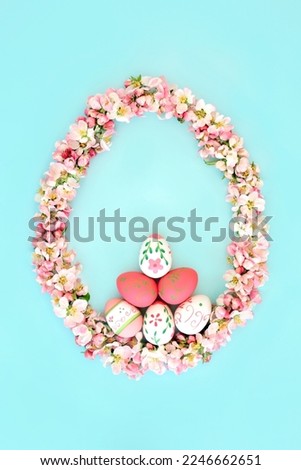 Abstract Easter egg shape with Spring apple blossom flowers and decorated eggs. Holiday, nature, fun, beautiful design concept on blue background. Flat lay.