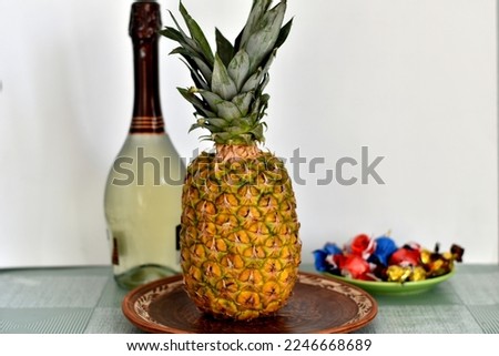 The picture shows a festive set of products, sparkling wine, pineapple and sweets.