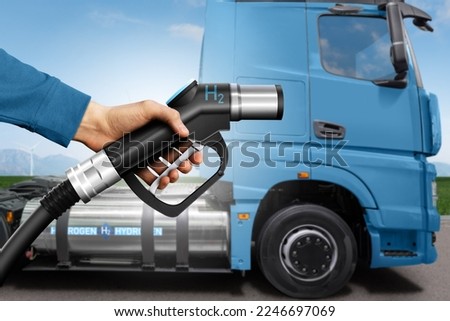 Hand with H2 fueling nozzle on a background of hydrogen fuel cell semi truck with gas tank onboard. Eco-friendly commercial vehicle concept Royalty-Free Stock Photo #2246697069