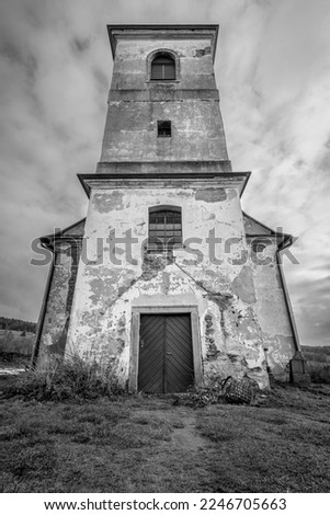 Vertical shot of old Church of Saint John of Nepomuk falling apart on a warm cloudy day of winter. Black and white image with dramatic low angle perspective. Mysterious, atmospheric, scary place. Royalty-Free Stock Photo #2246705663