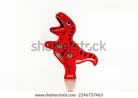 Red and Black hand made and painted childrens wooden toy T Rex Dinosaur isolated on a white backgroujnd